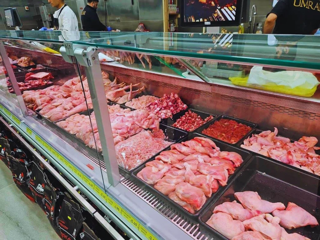 Fresh whole chicken and chicken cuts displayed in a hygienic retail meat shop.